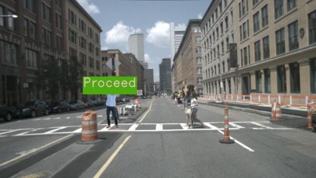 eine Straßenszene, darauf ein Mensch mit einem grünen "Proceed"-Schild