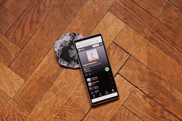 ein Smartphone mit Spotify auf einem Untertassengroßen gemusterten Polster