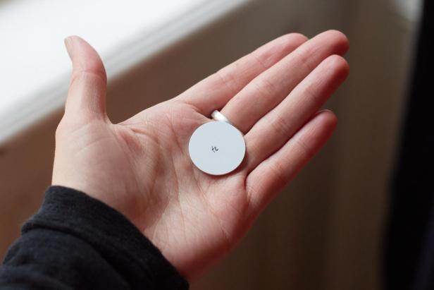 Eine Hand mit einem weißen kreisrunden NFC-Chip auf dem "fz" steht