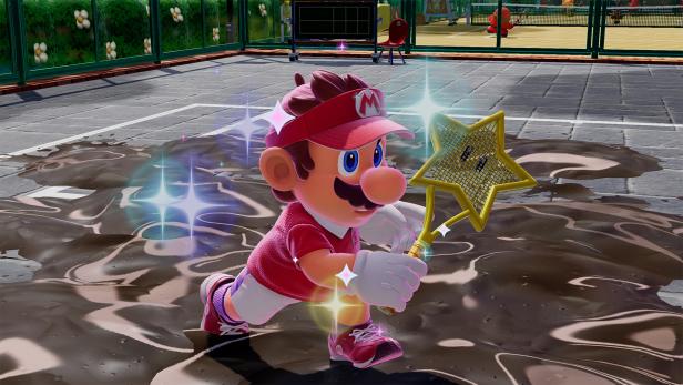 Mario im roten Tennis-Outfit mit Stern-Schläger auf einem matschigen Tennisplatz.