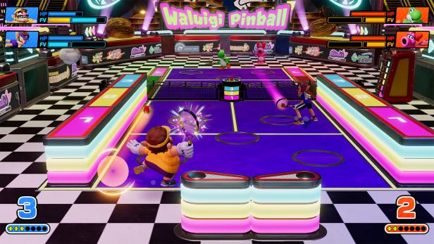 Vier Charaktere aus dem Mario-Universum spielen Tennis auf einem bunten, pinballartigen Court.