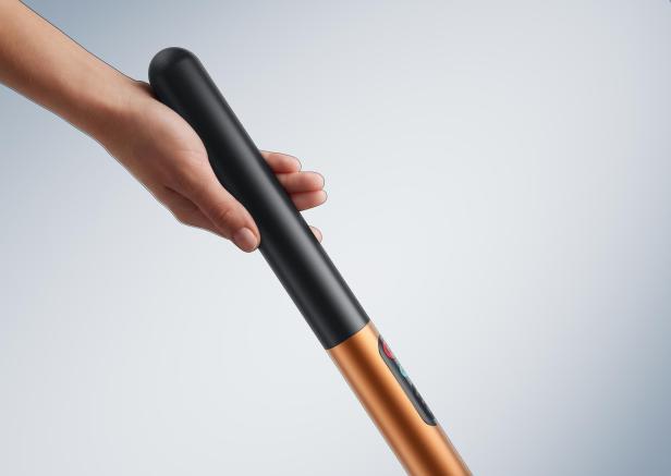 Hand hält den schlanken, schwarzen Griff eines Dyson PencilWash Nassreinigers.