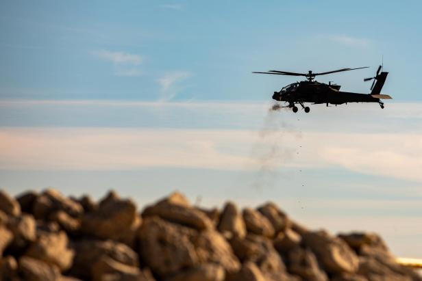 AH-64 feuert M230 ab, im Hintergrund sind Berge