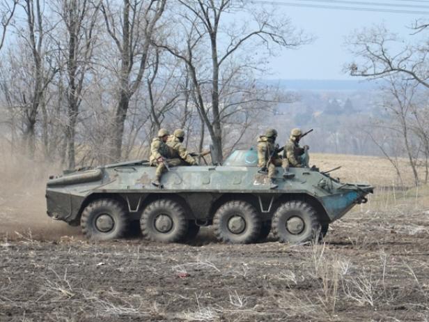Ukrainische Soldaten fahren auf einem gepanzerten BTR-60 durch unwegsames Gelände.