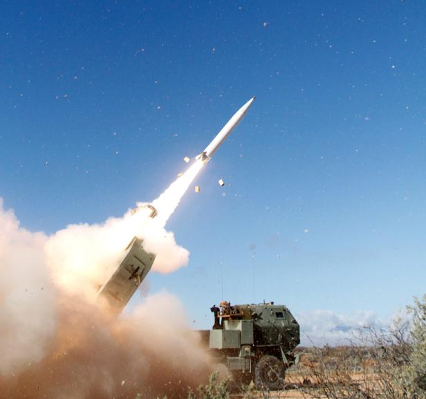 Raketenstart eines HIMARS-Systems in einer Wüstenlandschaft bei klarem Himmel.