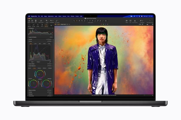 Ein MacBook zeigt eine Bildbearbeitungssoftware mit farbenfrohem Porträt auf dem Display.
