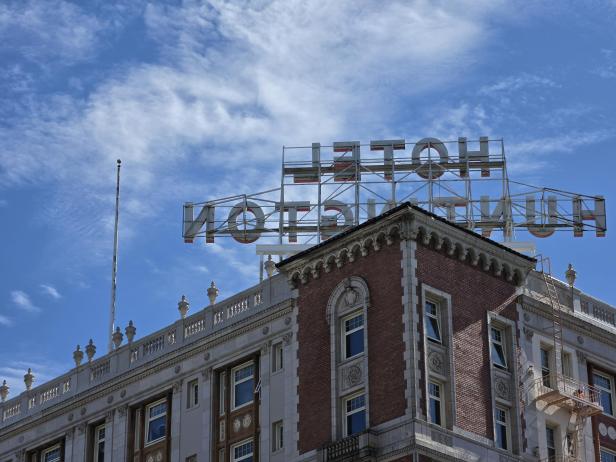 Hotelgebäude mit großem Schild auf dem Dach vor blauem Himmel mit Wolken.