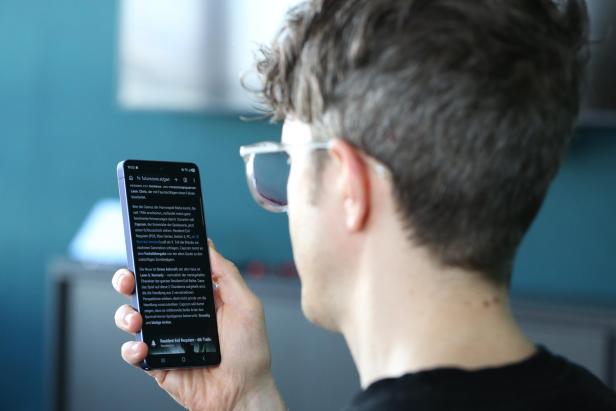 Eine Person hält ein Smartphone und liest Text auf dem Display.