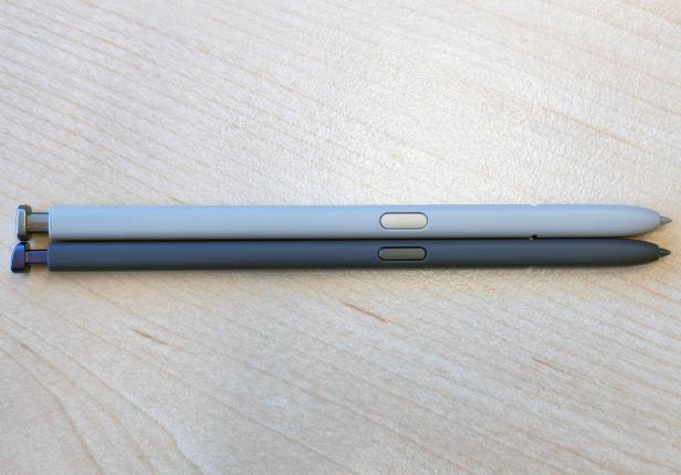 Zwei S Pens in unterschiedlichen Farben liegen nebeneinander auf einer Holzoberfläche.