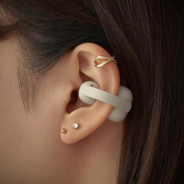 Ein Sony LinkBuds Clip Kopfhörer in Greige ist an einer Ohrmuschel befestigt und zeigt die spezielle Clip-Bauweise des Open-Ear-Modells.