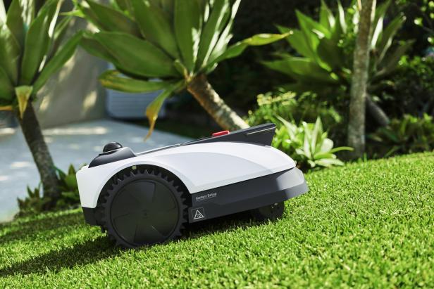 Ein Mähroboter auf einer Wiese, von der Seite 