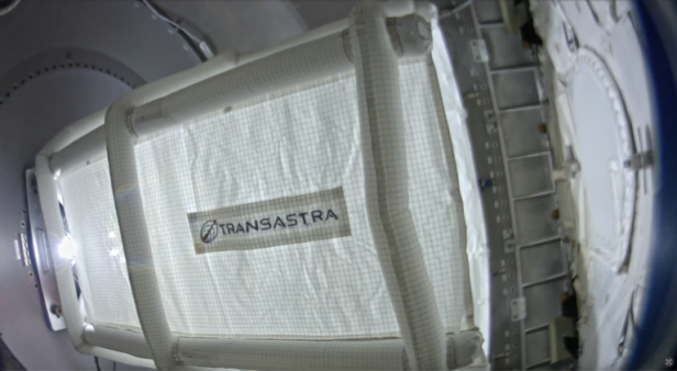 Eine große, aufblasbare Fangvorrichtung mit TransAstra-Logo ist im Inneren eines Raumschiffs montiert.