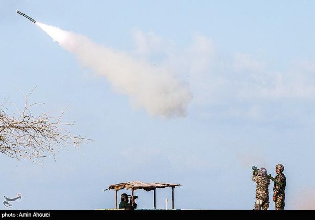 Zwei Soldaten feuern eine Boden-Luft-Rakete in den Himmel ab, Rauchspur sichtbar.