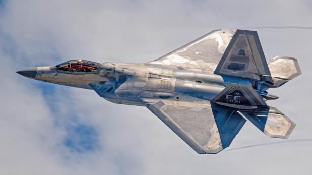 Ein Tarnkappen-Kampfjet fliegt mit hoher Geschwindigkeit durch den Himmel.