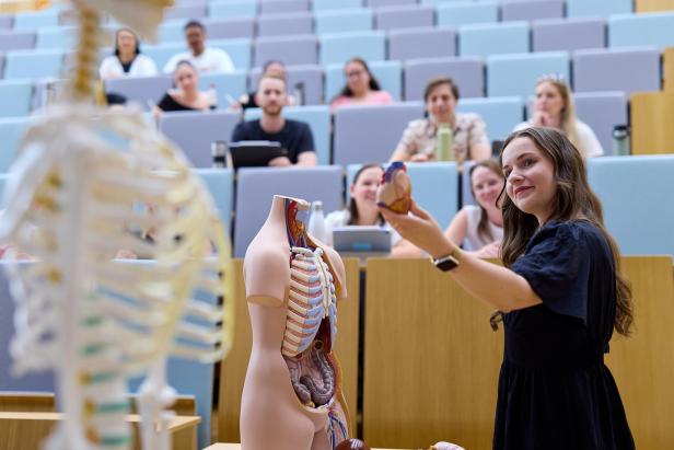 Dozentin erklärt Anatomiemodell vor Studierenden in einem Hörsaal.