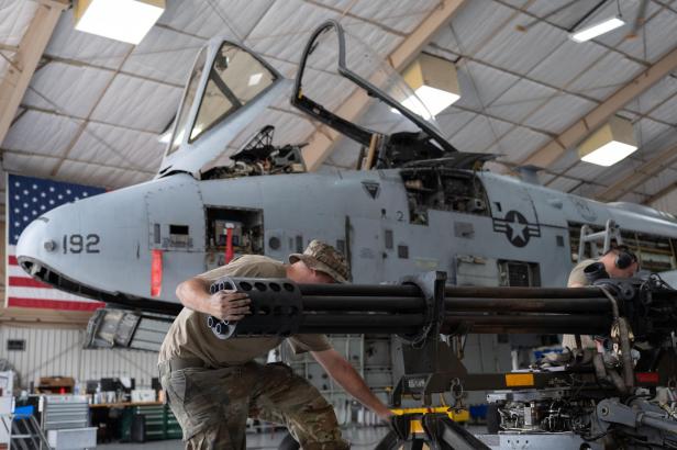 Mechaniker warten die GAU-8-Kanone vor einer demontierten A-10 in einem Hangar.