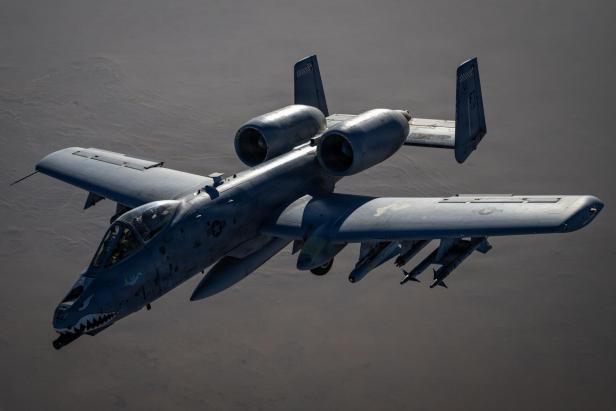 Kampfflugzeug A-10 Warthog mit markantem Haifischmaul im Flug über Wüstenlandschaft.