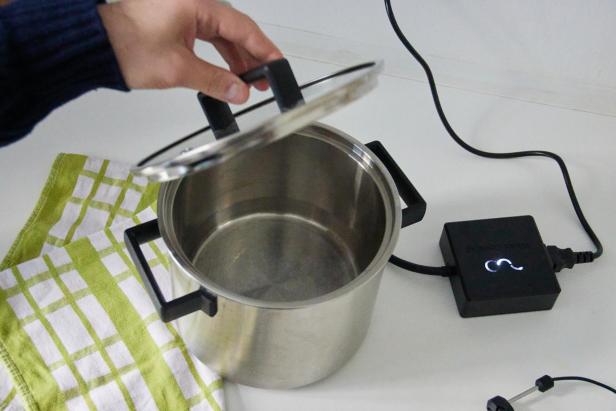 eine Hand hebt den Deckel des Wired Cookers an