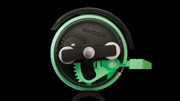 Detailansicht einer grünen Fahrradklingel mit sichtbarem Mechanismus und Škoda-Logo.