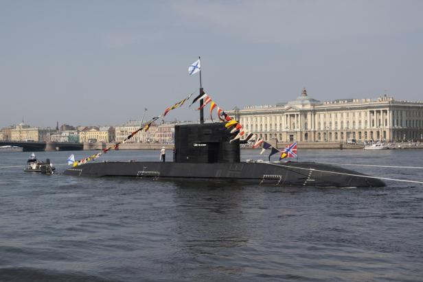Ein U-Boot fährt aufgetaucht in einem Fluss vor Häusern
