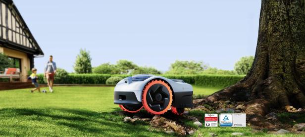 Der Segway Navimow i2 AWD Mähroboter mit TÜV Rheinland-Zertifizierung mäht sicher um Baumwurzeln, während im Hintergrund ein Kind mit einem Erwachsenen im Garten spielt.
