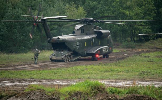 Ein Wiesel-Panzer verlässt einen CH-53G-Hubschrauber der Bundeswehr im Waldgelände.