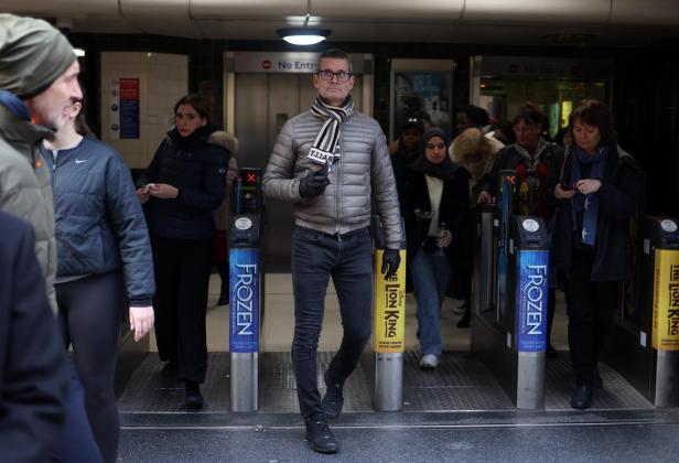 Mehrere Menschen verlassen eine U-Bahn-Station durch Drehkreuze, einige tragen Winterkleidung und halten Fahrkarten in der Hand.