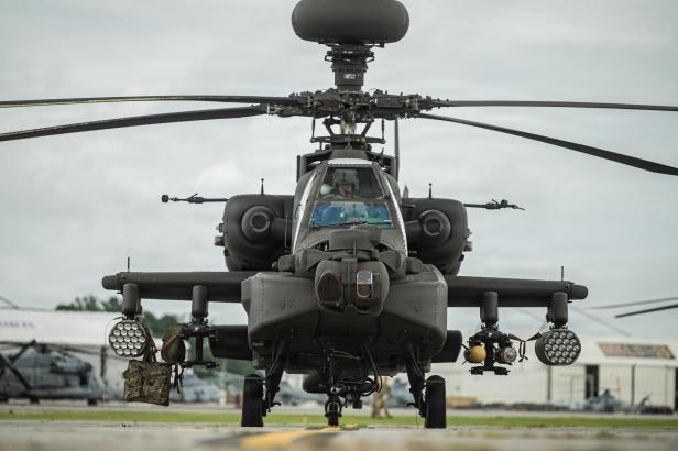 Kampfhubschrauber mit Raketenbewaffnung und Sensoren auf einem Flugfeld bei bewölktem Himmel.