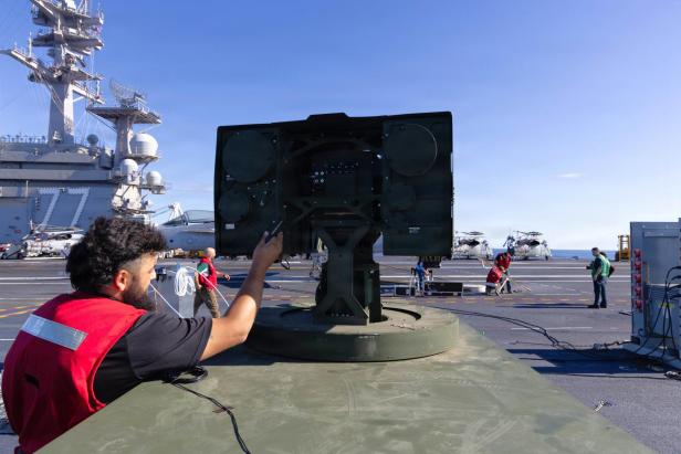 Ein Mann arbeitet am Turm der Locust Laserwaffe, die auf einem Flugzeugträger steht