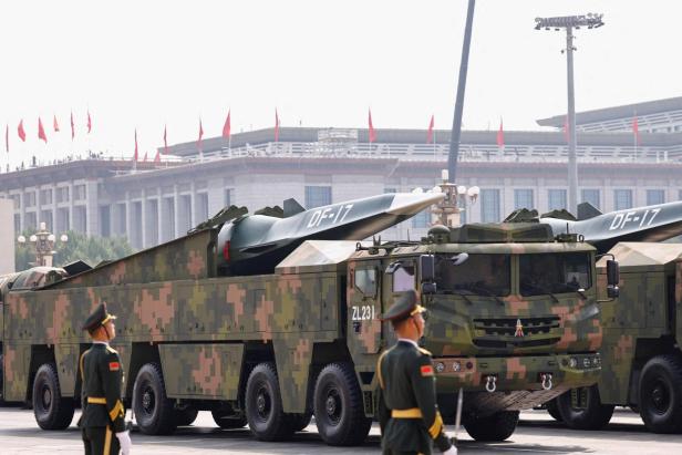Tarnfarbene Militärfahrzeuge mit Raketenaufsätzen und der Aufschrift „DF-17“ werden von Soldaten bewacht.