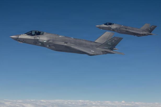 Zwei Kampfjets fliegen in Formation über einer Wolkendecke am Himmel.