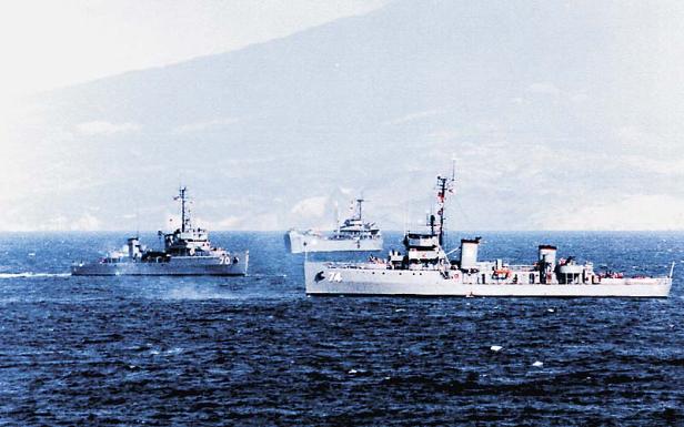 3 Kriegsschiffe sind am Meer zu sehen, im Hintergrund ist die Küste