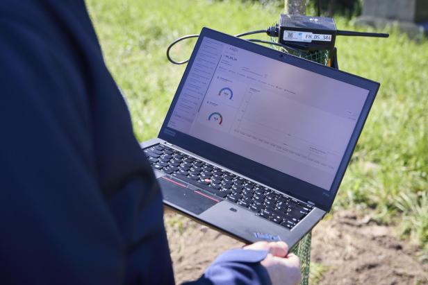 EIn Notebook zeigt Temperatur und Feuchtigkeitsgehalt des Bodens, gemessen mit einem Sensor, der in der Erde vergraben wurde.