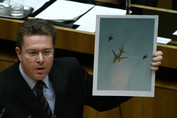 Ein Mann hält ein Foto hoch, das ein Tankflugzeug und zwei Stealth-Jets zeigt