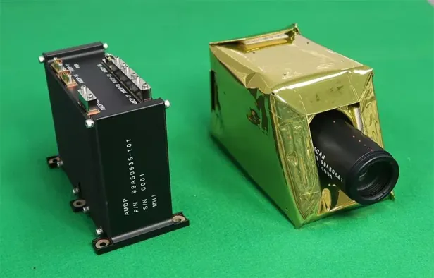 Der KI-Datenprozessor und die Erdbeobachtungskamera des AIRIS-Detektors von Mitsubishi und der Tokyo University of Science liegen nebeneinander auf grünem Untergrund.