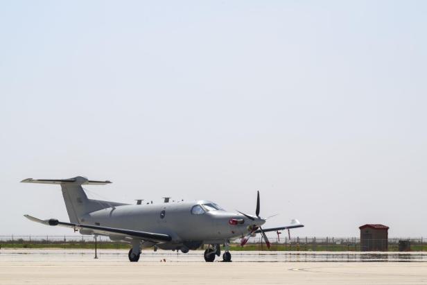 Ein graues U-28A Draco Aufklärungsflugzeug steht auf dem Rollfeld eines Flughafens.