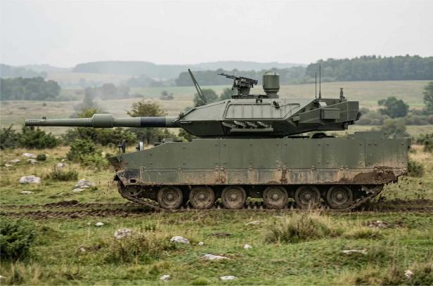Seitenansicht eines grünen Panzers, der in der Wiese fährt