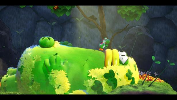 Der grüne Saurier Yoshi steht auf einer großen grünen Kreatur, die im Wald am Boden liegt