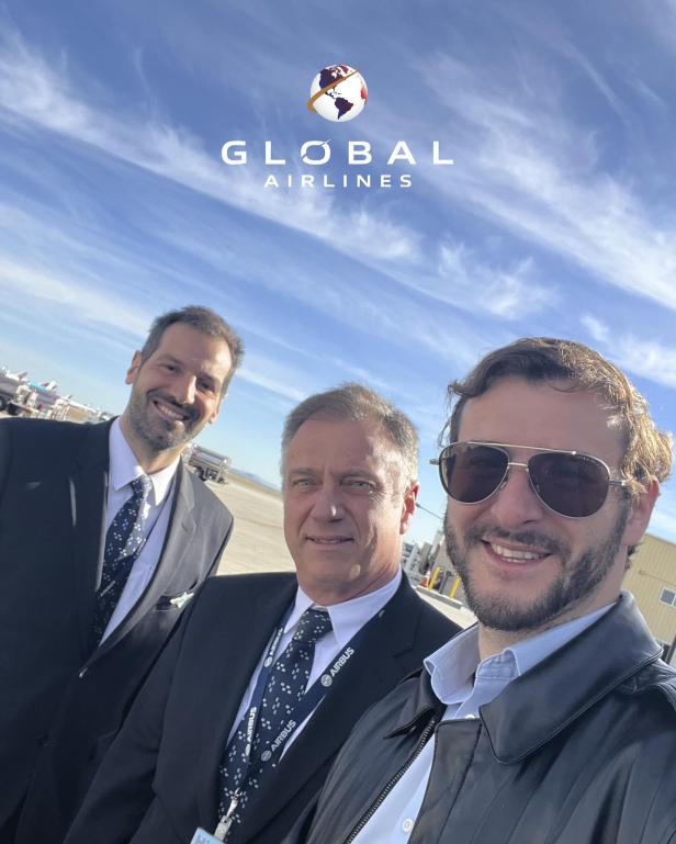 Drei Männer, darunter Vertreter von Global Airlines und Airbus, stehen gemeinsam auf dem Rollfeld vor blauem Himmel.