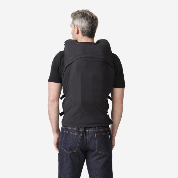 Ein Mann trägt die schwarze, ärmellose Airbag-Weste von Decathlon und In&motion mit sichtbarer Elektronik am Rücken.