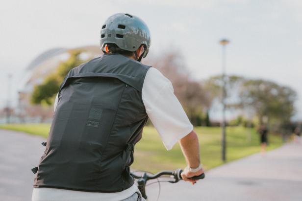 Ein Mann trägt die schwarze, ärmellose Airbag-Weste von Decathlon und In&motion mit sichtbarer Elektronik am Rücken.