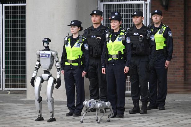 Fünf Polizisten stehen nebeneinander, davor ein humanoider Roboter und ein vierbeiniger Roboterhund.