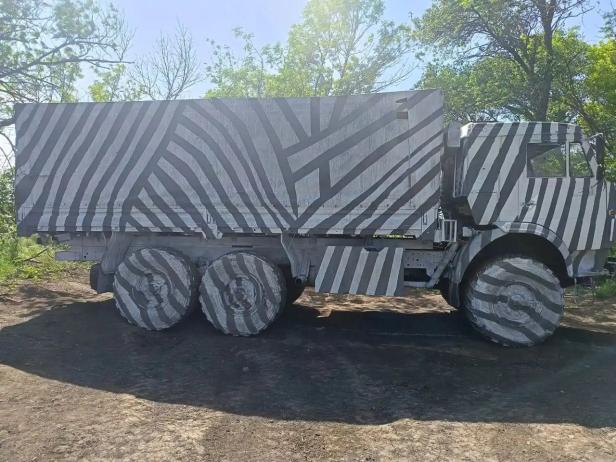 Ein russische Lkw mit Zebra-Muster steht im Wald