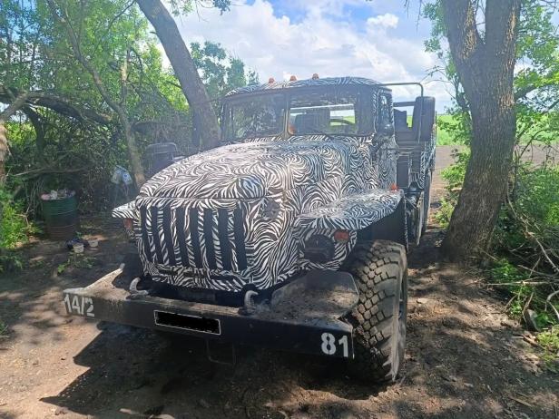 Ein russischer Lkw des Typs Ural mit Zebratarnung steht im Wald