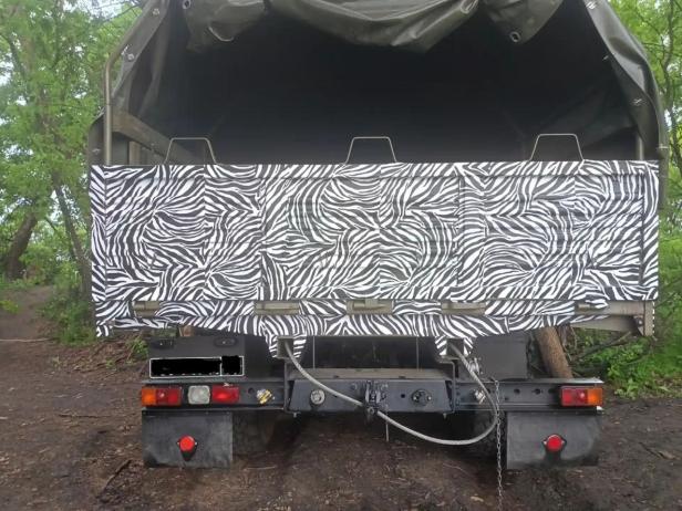 Ein russischer Lkw des Typs Ural mit Zebratarnung steht im Wald.