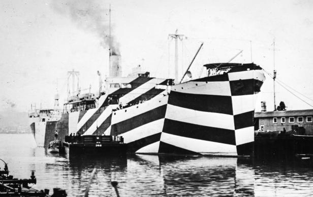 Ein Kriegsschiff mit Zebramuster-Tarnung steht im Hafen