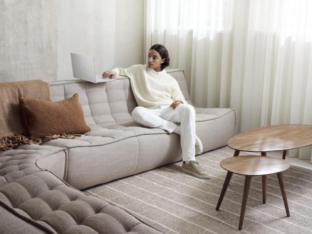 Frau sitzt auf Sofa mit Laptop 