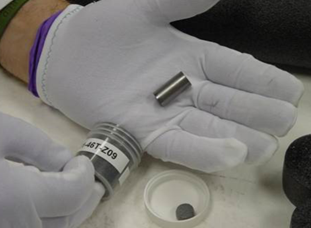 Ein silbernes Pellet in Zylinderform wird in einer Hand gehalten