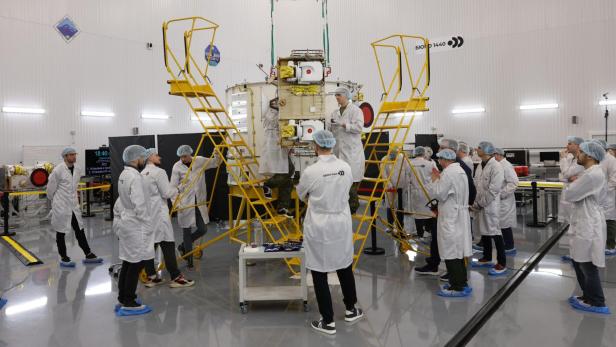 Menschen in Kitteln stehen um ein technisches Gerät