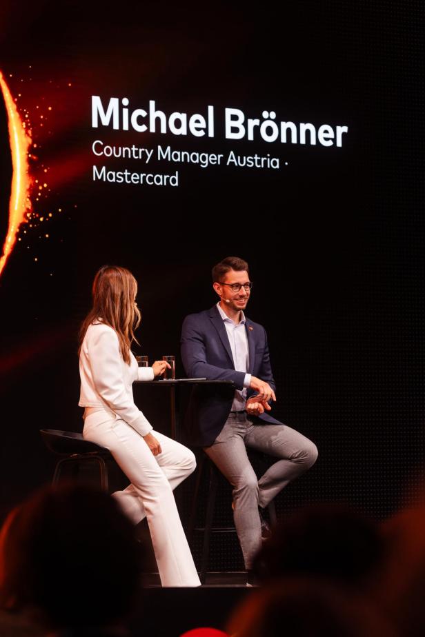 Michael Brönner, Country Manager Austria von Mastercard, spricht beim Innovation Forum 2026 auf der Bühne mit einer Moderatorin.